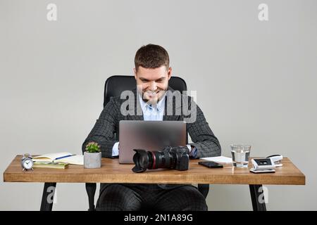 bearded male photographer smiling while working at her desk. Stock Photo