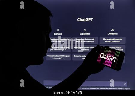 Kaunas, Lithunaia - 2022, February 5: Man silhouette holding smartphone with ChatGPT logo. ChatGPT is AI chatbot which is made by OpenAI. Stock Photo