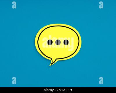 Three dots on yellow speech bubble on blue background. Discussion, social media chat or comment concept. Stock Photo