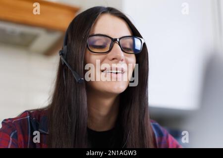 Portrait of cheerful young woman wearing headset with microphone. Friendly online support operator talks to client on a phone call Stock Photo