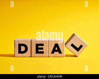 The word Deal on wooden cubes with yellow background. Business deal concept. Stock Photo