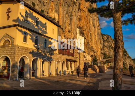 Façade of the upper church and Ostrog Monastery bathed in golden light at sunset in Montenegro Stock Photo