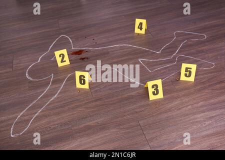 Crime scene with chalk outline of human body, blood, bullet shells and evidence markers on wooden floor. Detective investigation Stock Photo