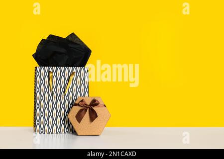 Shopping bag and gift box on yellow background. Space for text Stock Photo
