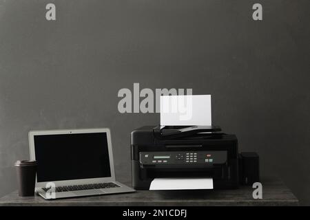 Modern printer with paper and laptop on grey table Stock Photo