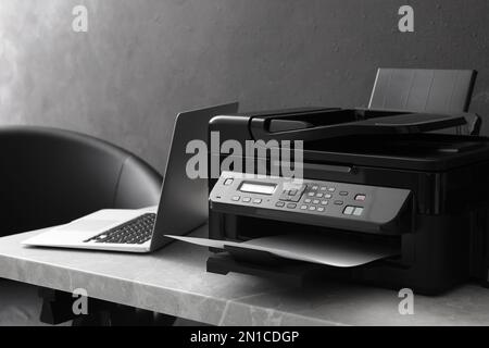 New modern printer and laptop on grey table indoors Stock Photo