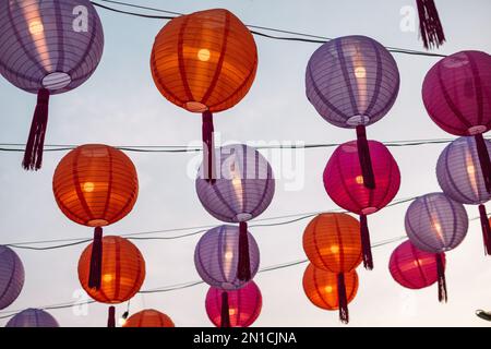 The bright paper lanterns hanging in the sky over the trees in Bangkok Stock Photo