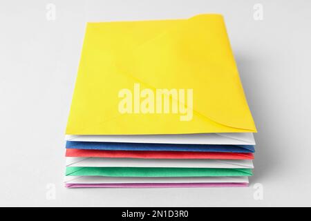 Stack of colorful paper envelopes on light background Stock Photo