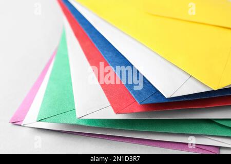 Stack of colorful paper envelopes on light background, closeup Stock Photo