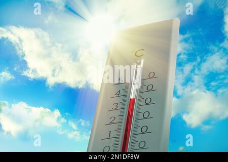 Wooden thermometer with red measuring liquid showing high temperature over  32 degrees Celsius on background of blue sky with clouds. Concept of heat w  Stock Photo - Alamy