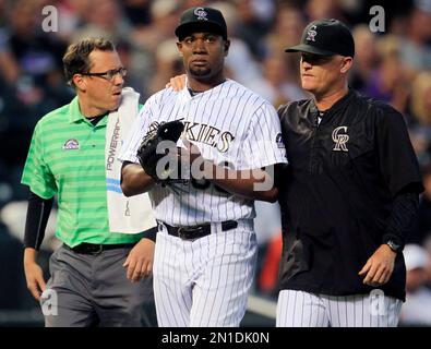 Colorado Rockies' Charlie Blackmon, left, shows to trainer Scott Gehret  where a foul ball hit his batting helmet as he stood in the on-deck circle,  during the third inning of the team's