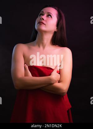 Beautiful woman covers itself by a red cloth. Stock Photo