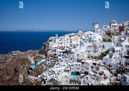 Windmills, houses and hotels in the town of Oia, on the clifftop overlooking the caldera, Santorini, The Cyclades, Aegean Sea, Greek Islands, Greece Stock Photo