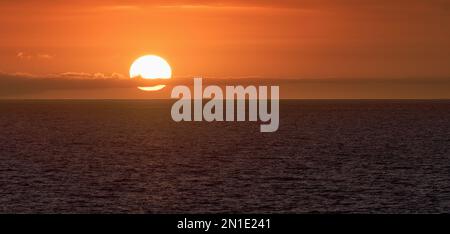 Sun is setting on horizon at sunset sunrise over sea or ocean. Tranquil sea ocean waves Stock Photo