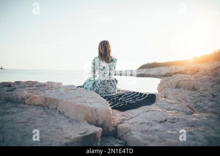 Lonely young woman sitting on beach Stock Photo