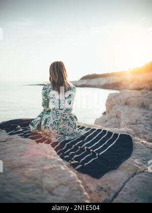 Lonely young woman sitting on beach Stock Photo