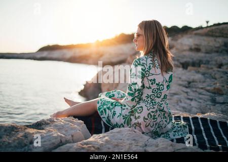 Lonely young woman sitting on beach Stock Photo