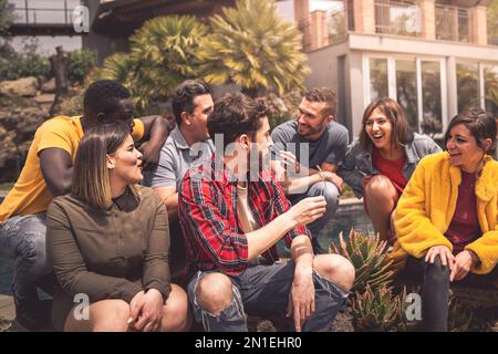 A diverse group of friends is seated on outdoor steps, chatting and enjoying each other's company. The scene highlights the value of friendship and th Stock Photo