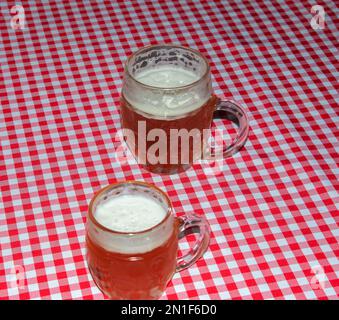 A mug of beer on a table covered with a red checkered tablecloth. Stock Photo