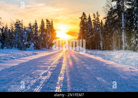 Sunset over an empty snowy road, Lapland, Finland, Europe Stock Photo