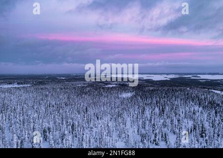 Aerial view of a snowy Arctic landscape at sunset with a small building ...