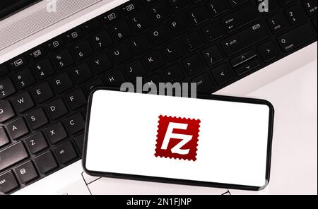 File transfer protocol software on mobile screen with laptop in the backdrop, filezilla editorial background Stock Photo