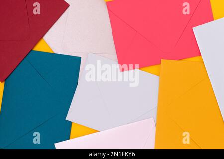 Multicolored envelopes scattered on a yellow background. Creative background. Stock Photo