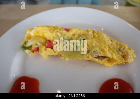 Fluffy breakfast omelet with gravy on white plate Stock Photo