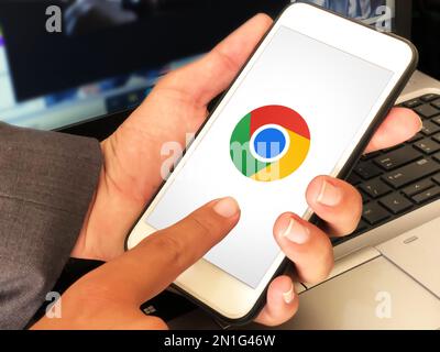 Man using google chrome application on mobile with laptop in the backdrop, browser editorial background Stock Photo
