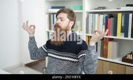 Young redhead man student doing yoga exercise relaxing at library university Stock Photo