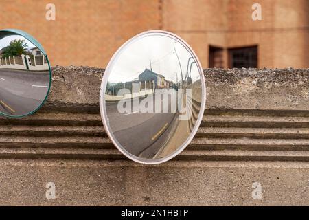 Round convex traffic safety mirror reflecting a rural street. Stock Photo
