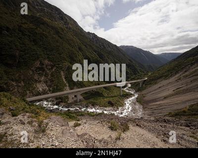 Cars driving on Otira Viaduct concrete bridge over green alpine valley river at Arthurs Pass Southern Alps Westland West Coast South Island of New Zea Stock Photo