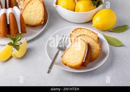 Lemon bundt cake drizzled with powdered sugar glaze topped with lemon zest sliced Stock Photo