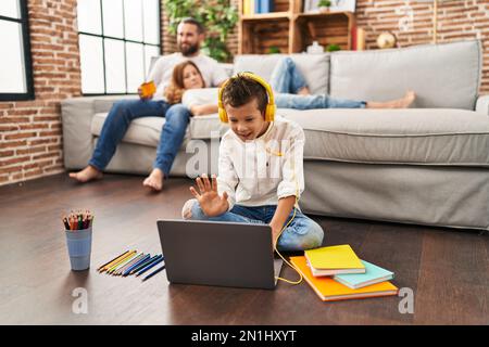 Family of three doing homework at home looking positive and happy standing and smiling with a confident smile showing teeth Stock Photo
