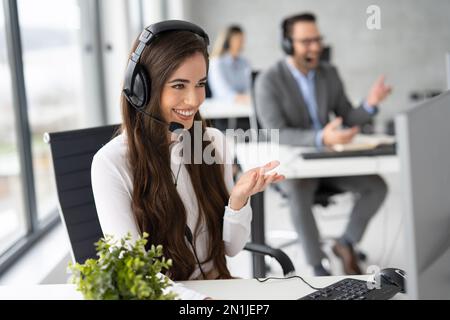 Beautiful business woman in headset working at customer service office. Stock Photo