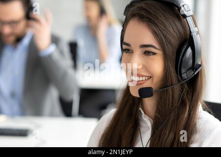 Headshot of beautiful young woman talking to client in a call center. Stock Photo