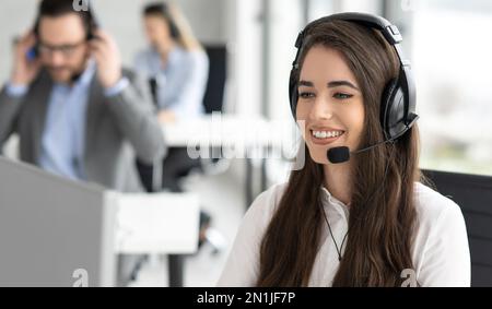Close up portrait of friendly smiling customer support operator female working at helpdesk office Stock Photo