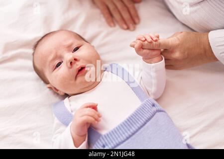 Mother and son lying on bed holding hands at bedroom Stock Photo