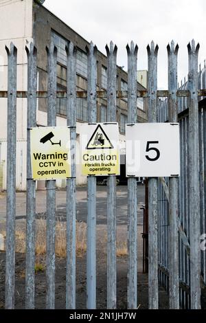 Warning CCTV in operation and Caution Forklift trucks operating signs on the exterior fence of an industrial building, Scotland, UK, Europe Stock Photo