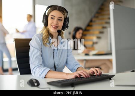 Beautiful customer support representative woman using computer in customer service office Stock Photo