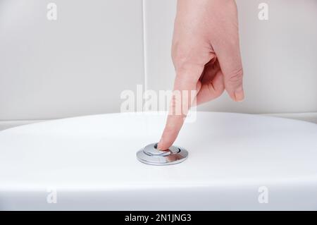 Hand pushing a button to flush a close tool Stock Photo