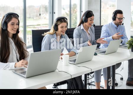 Group of friendly customer care support operators working in call center. Stock Photo