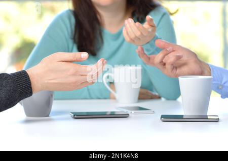 Three friends hands talking in a bar and disconnected from social networks with the phone on the table Stock Photo
