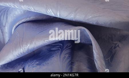 silver blue vegetal print fabric lying in soft folds as an abstract texture background, fabric backdrop made of shiny bluish synthetic material Stock Photo