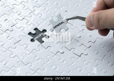 A hand pick a piece of jigsaw puzzle written with General and an empty space of jigsaw puzzle written with Specific. Stock Photo