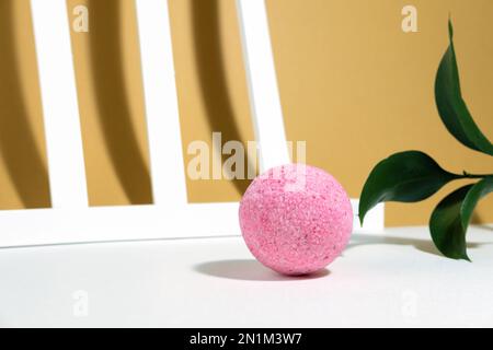 Pink salt bomb on a creative orange beige white background, with geometric lines, plant and hard shadows. Mineral cosmetics creative layout. Spa care. Stock Photo