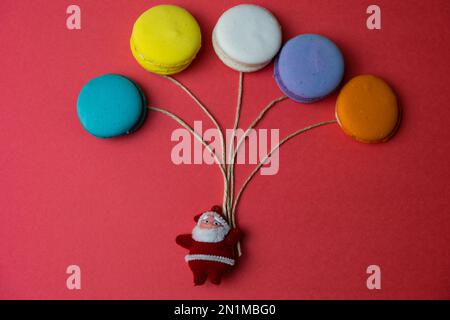 Balloon-shaped colorful macarons, christmas concept with red background, Santa Claus, top view. Stock Photo