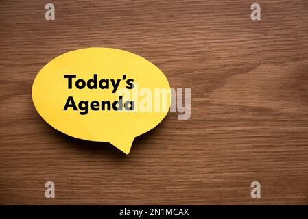 Top view of yellow speech bubble written with Today's Agenda on wooden background with copy space. Stock Photo