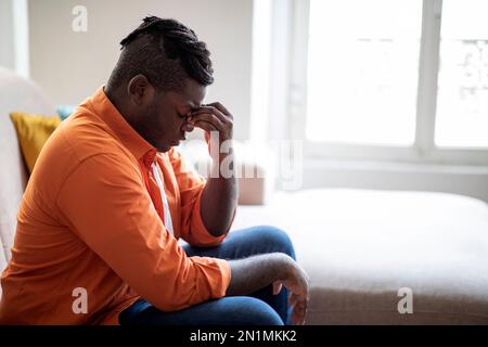 Upset stressed young african man having strong headache, side view Stock Photo