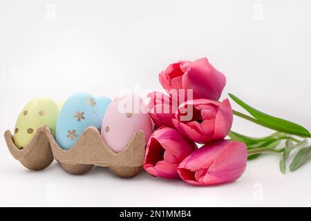 Pink tulips with colored eggs on white background. Easter. Copy space Stock Photo